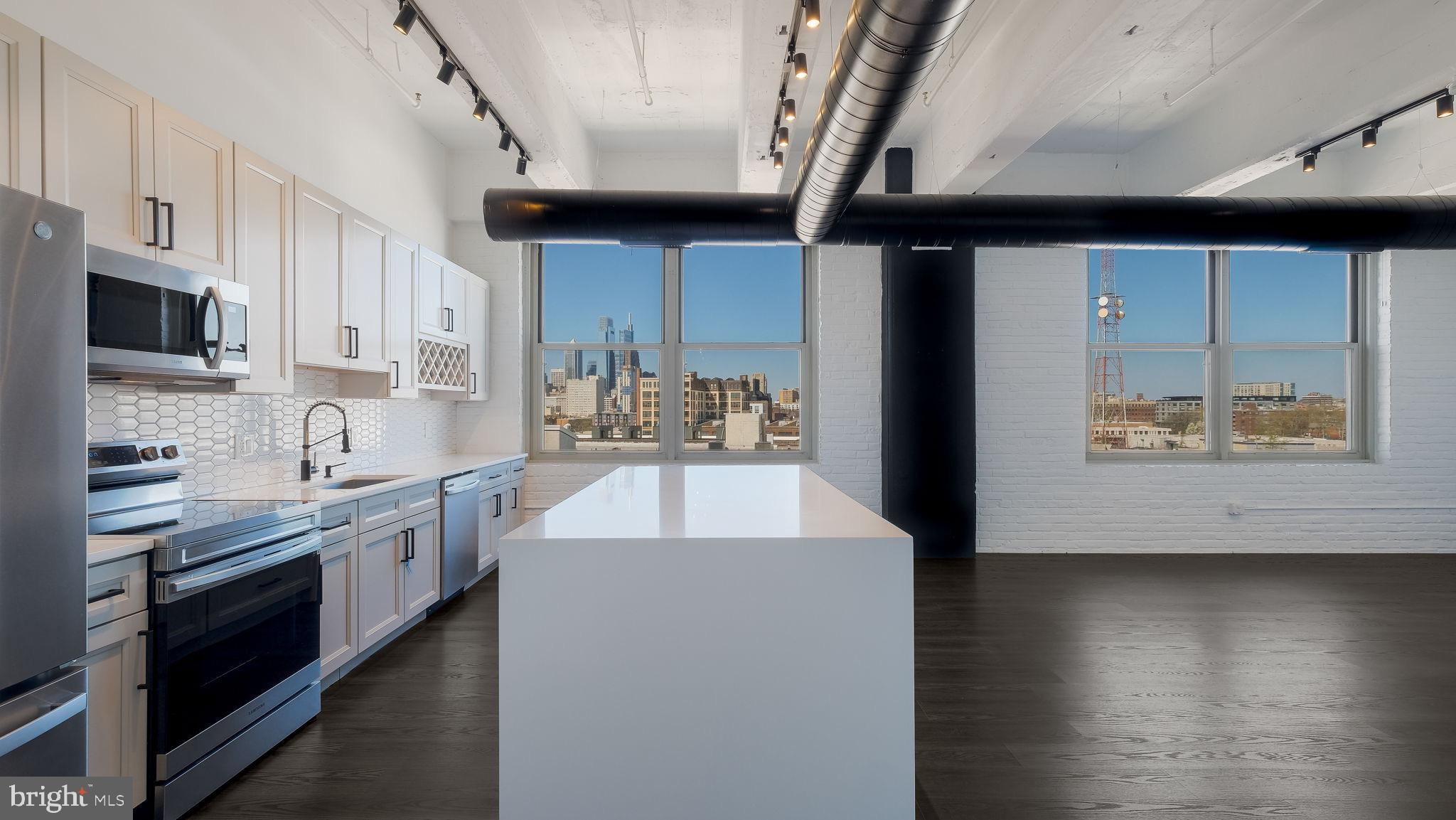 444 North 4th Street, Unit 601 Philadelphia, PA 19123 - Photo 3 of 38 a large kitchen with stainless steel appliances kitchen island granite countertop a stove a sink and a microwave