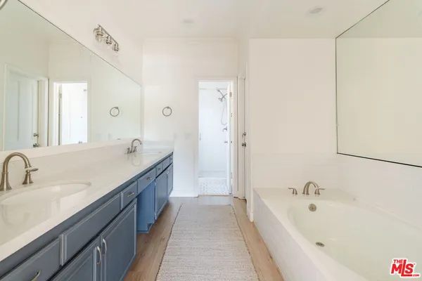 a spacious bathroom with a tub sink and mirror