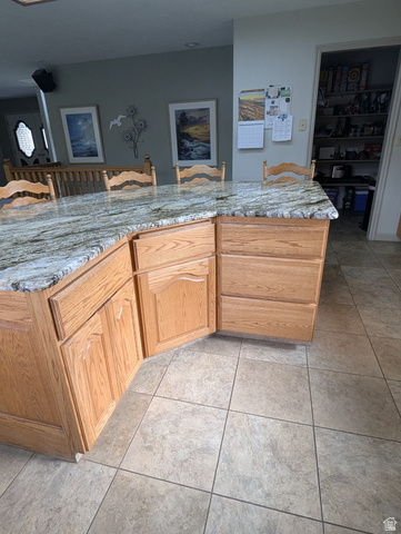 1040 West Mill Road Ferron, UT 84523 - Photo 19 of 117 Kitchen island featuring a stone-finish countertop, wood cabinetry, and tile flooring