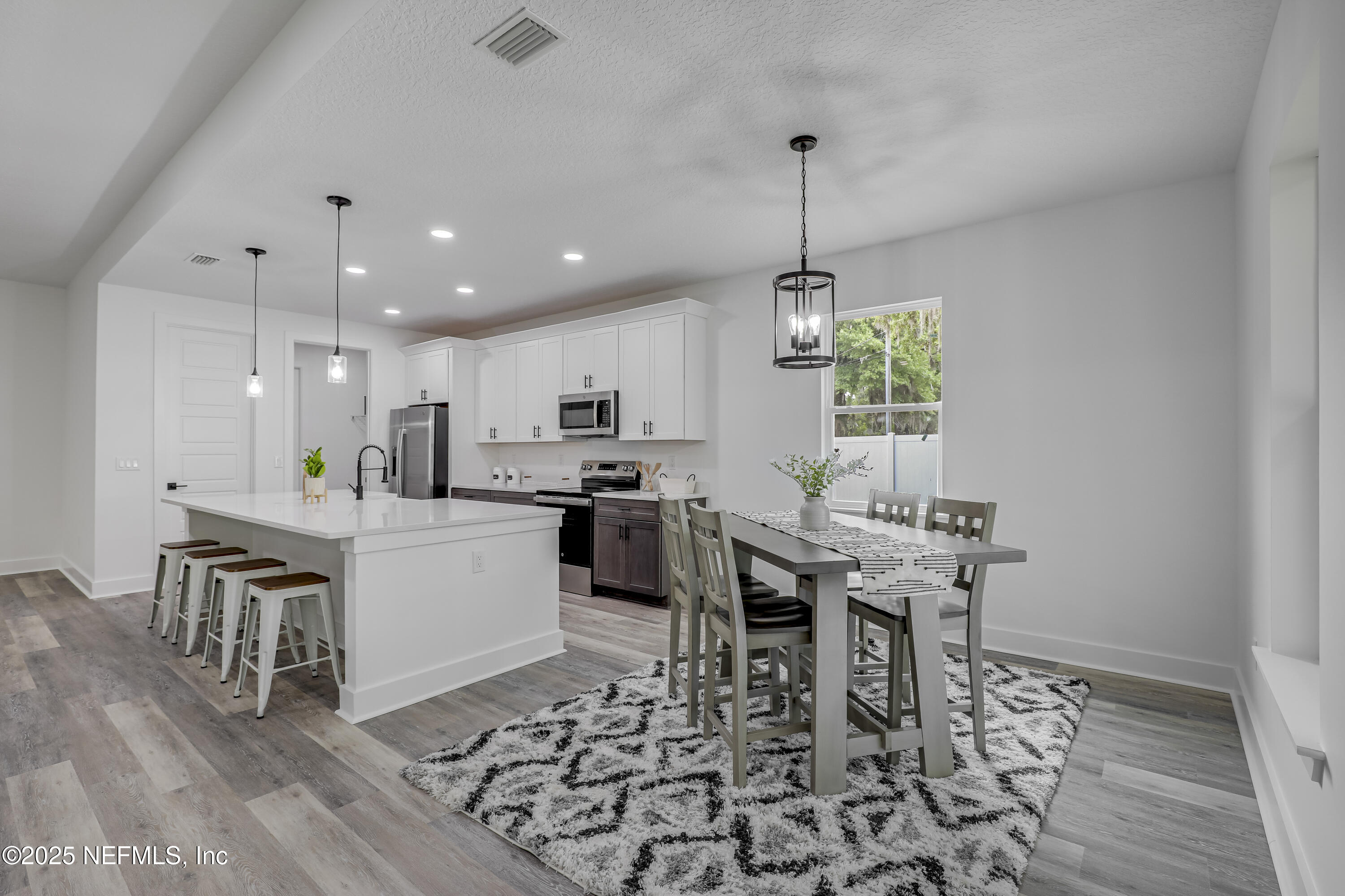12092 Sheffield Road Jacksonville, FL 32226 - Photo 5 of 55 a kitchen with stainless steel appliances kitchen island granite countertop a stove a sink a dining table and chairs with wooden floor