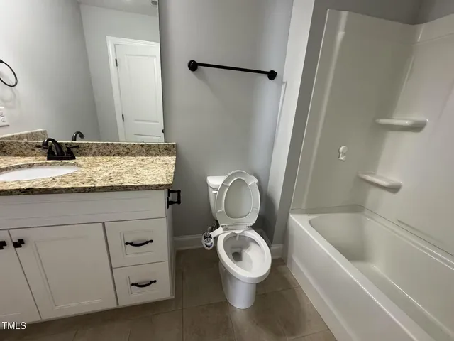 a bathroom with a granite countertop toilet sink and mirror