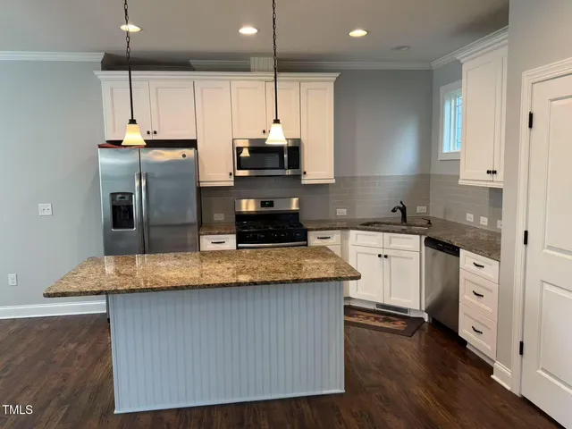 a kitchen with kitchen island granite countertop a sink cabinets and stainless steel appliances