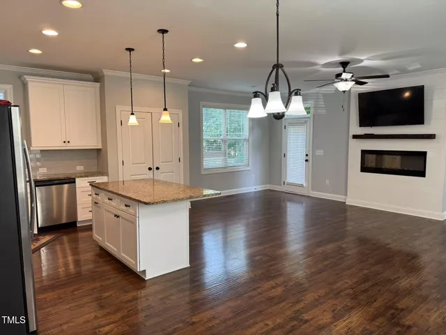 a large kitchen with granite countertop a stove a sink a center island and wooden floor