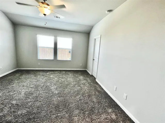 an empty room with a chandelier fan and windows