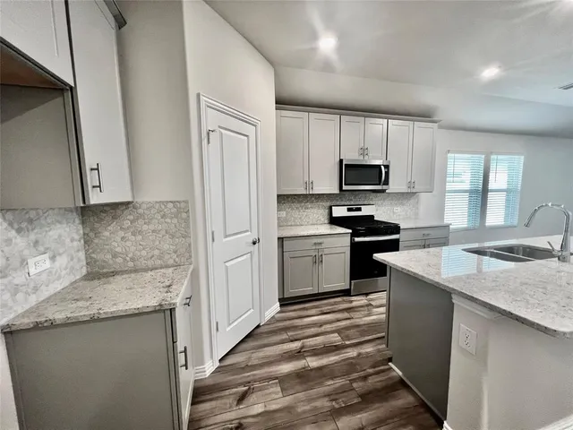 a kitchen with a sink stove top oven and refrigerator