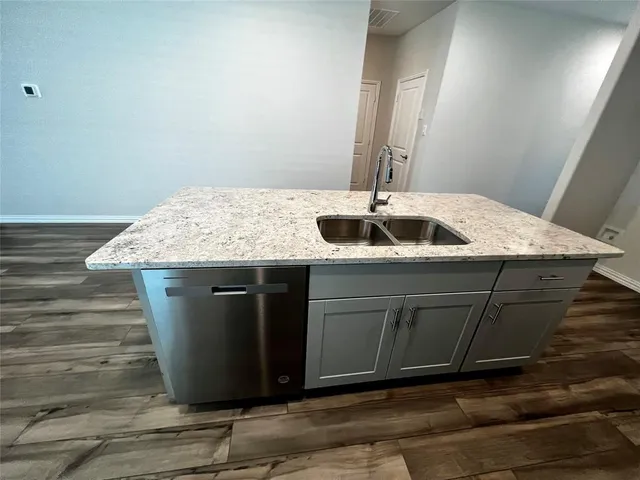 a kitchen with granite countertop white cabinets and a stove top oven