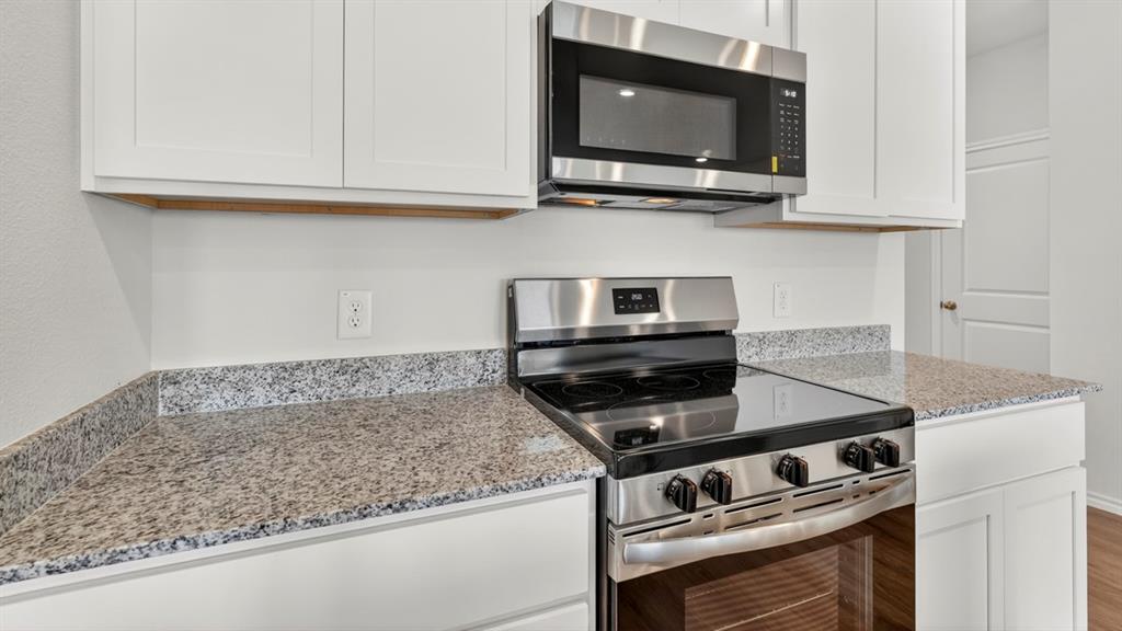 1683 Mantle Road Crandall, TX 75114 - Photo 7 of 31 Kitchen featuring white shaker cabinetry, speckled countertops, stainless steel range, and a coordinating stainless steel microwave