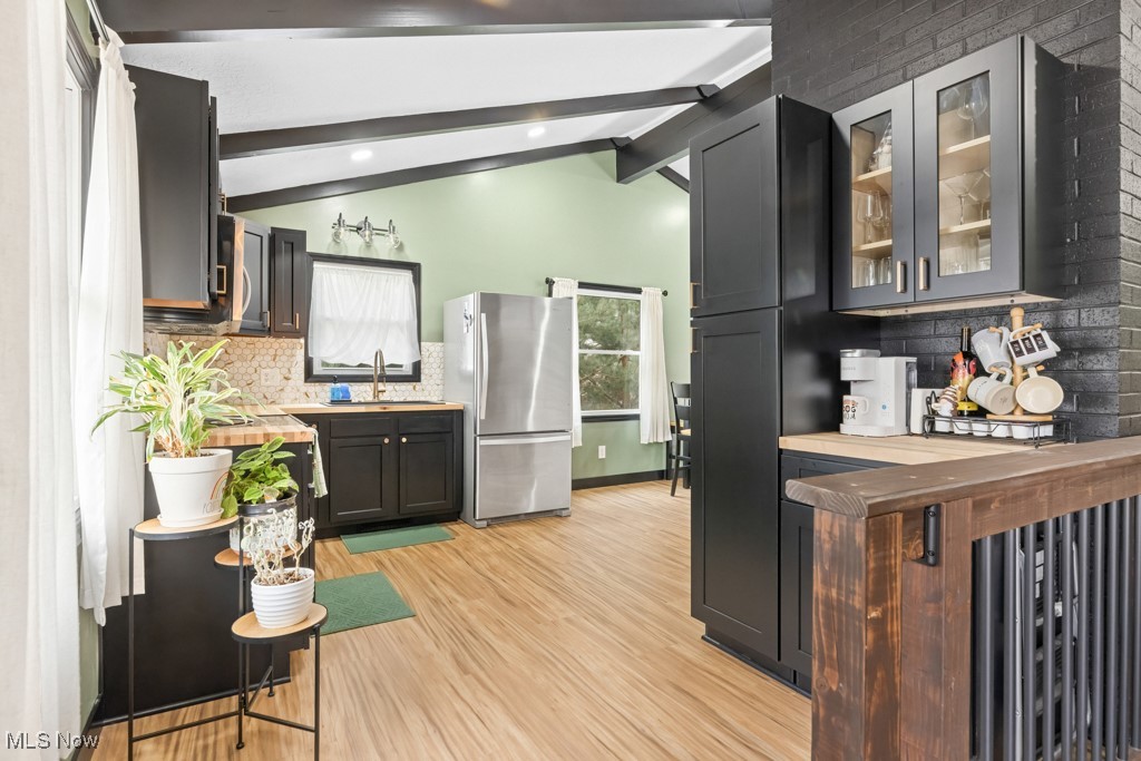 4551 17th Street Northwest Canton, OH 44708 - Photo 5 of 39 Kitchen featuring vaulted ceiling with beams, light wood-style flooring, glass insert cabinets, freestanding refrigerator, and a sink