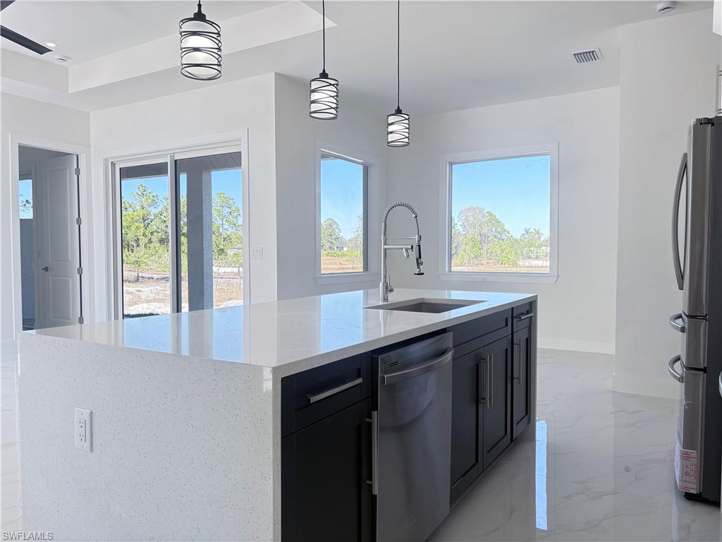423 Harshaw Street Lehigh Acres, FL 33974 - Photo 6 of 27 a kitchen with stainless steel appliances granite countertop a sink refrigerator and window