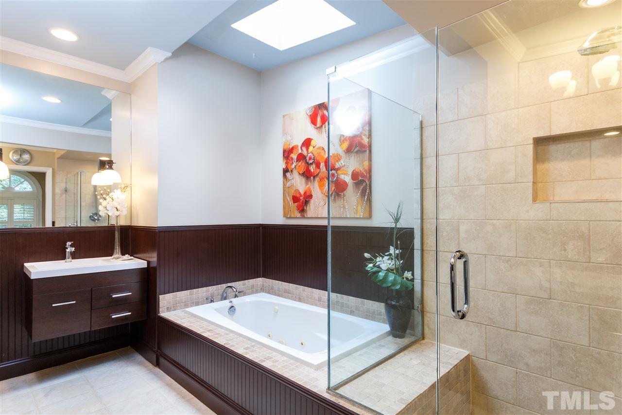 812 Misty Isle Place Raleigh, NC 27615 - Photo 14 of 25 a bathroom with a tub a sink and glass door