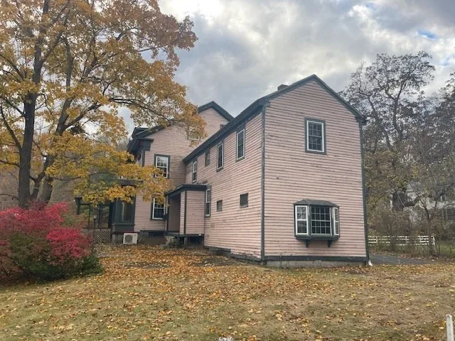 a view of a white house with a large tree