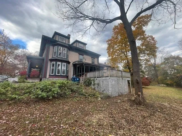 a view of a large house with a yard and wooden fence