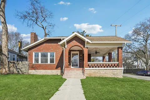 a front view of a house with a garden and trees