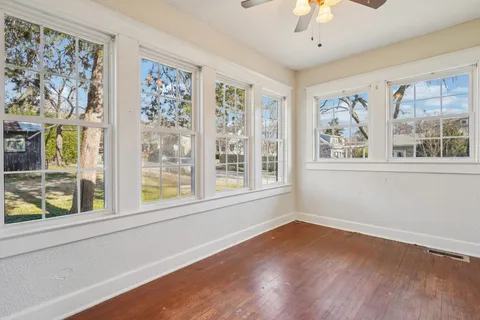 a view of an empty room with wooden floor and a window