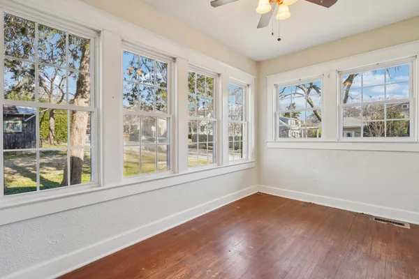 a view of an empty room with wooden floor and a window