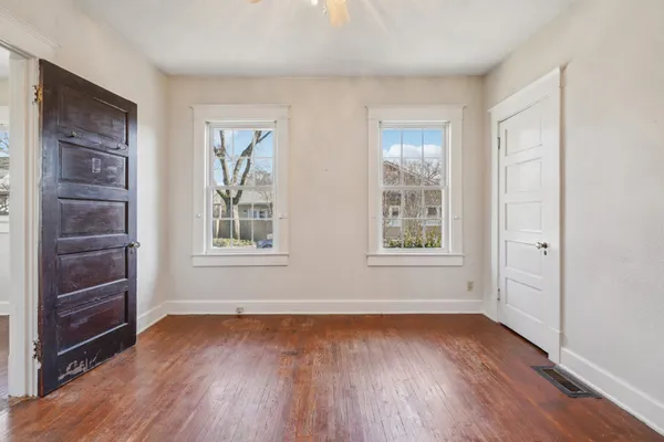 an empty room with wooden floor fan and windows
