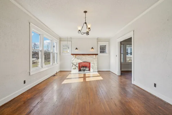 a view of a room with wooden floor fireplace and windows