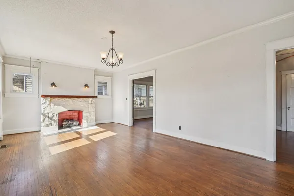 an empty room with wooden floor fireplace and windows