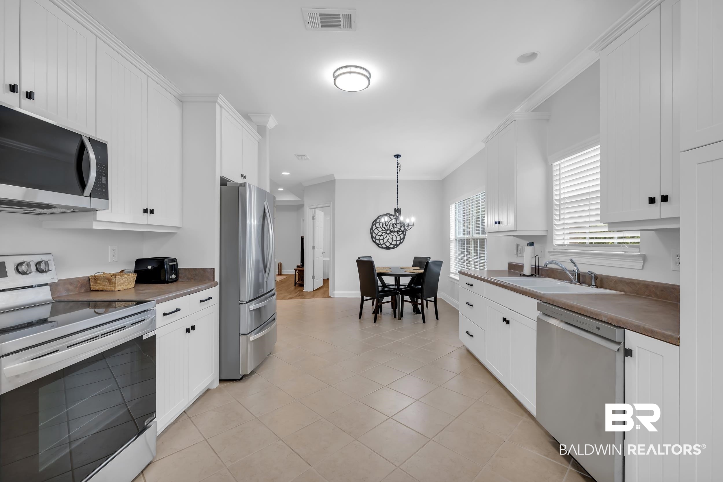 105 Mark Twain Loop Foley, AL 36535 - Photo 4 of 43 Kitchen featuring appliances with stainless steel finishes, ornamental molding, dark countertops, white cabinetry, and hanging light fixtures