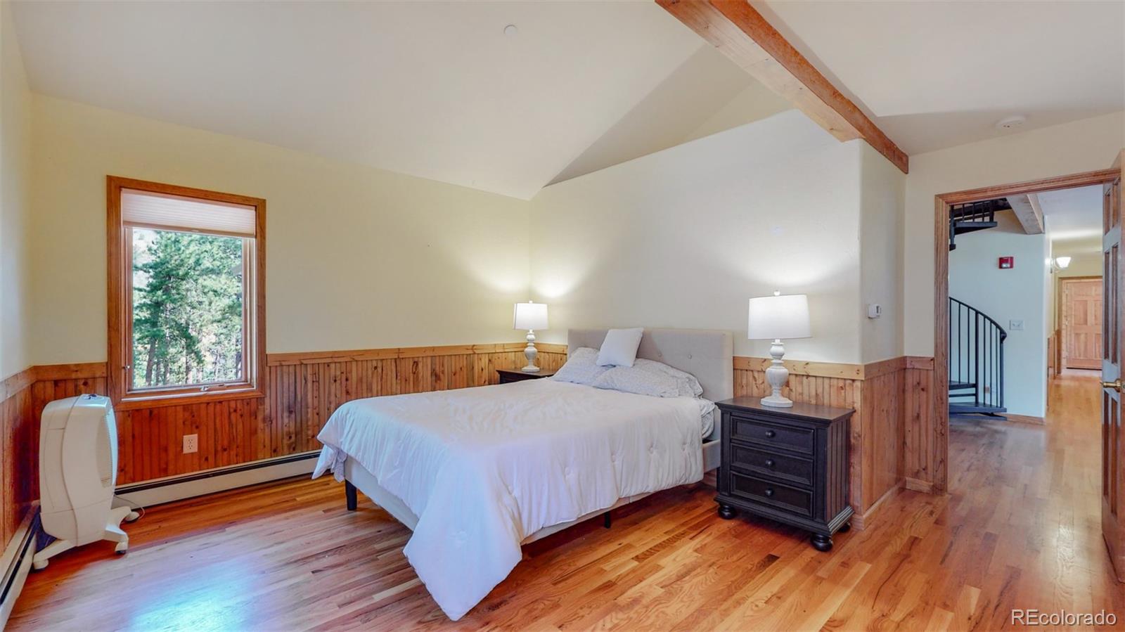 153 Ski Road East Allenspark, CO 80510 - Photo 22 of 40 a bedroom with a bed wooden floor and windows