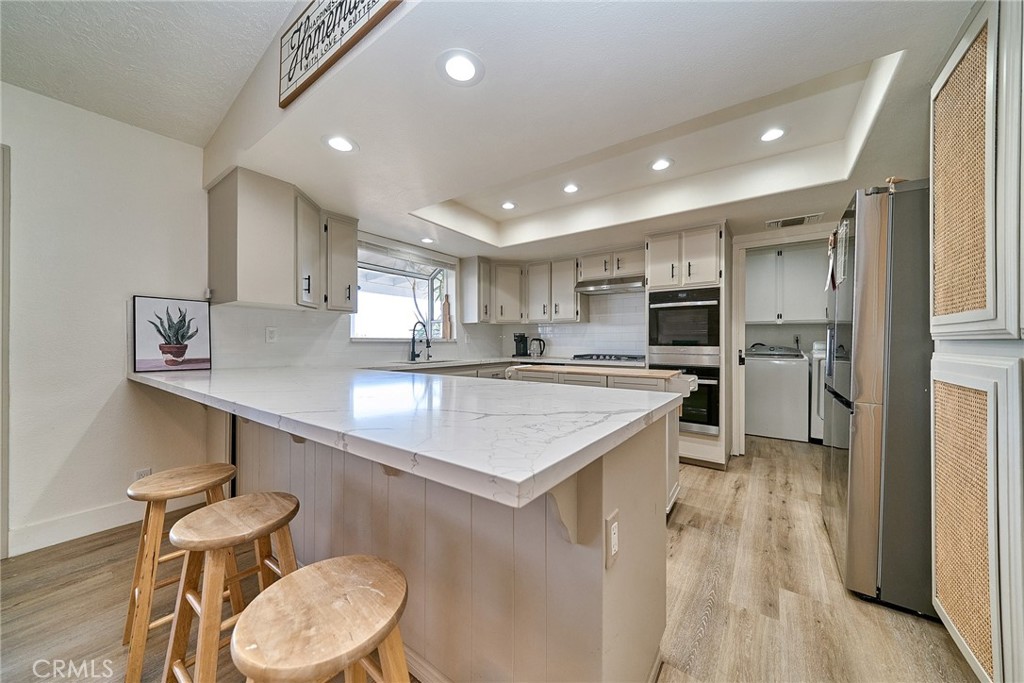 9783 Corton Street Phelan, CA 92371 - Photo 13 of 29 a kitchen with stainless steel appliances a sink a stove a refrigerator cabinets and chairs