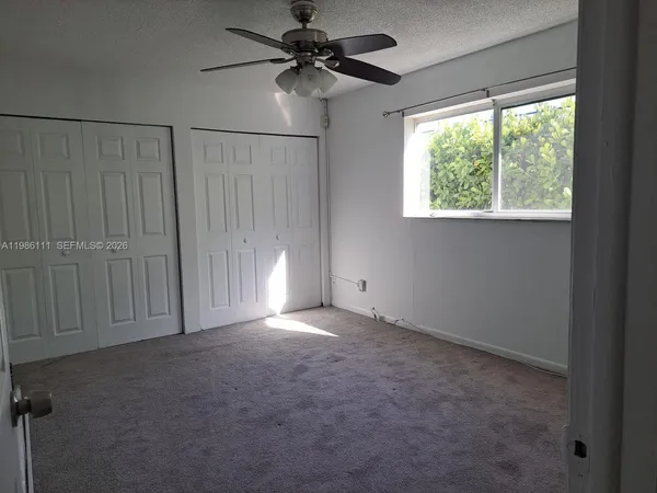 an empty room with windows and fan