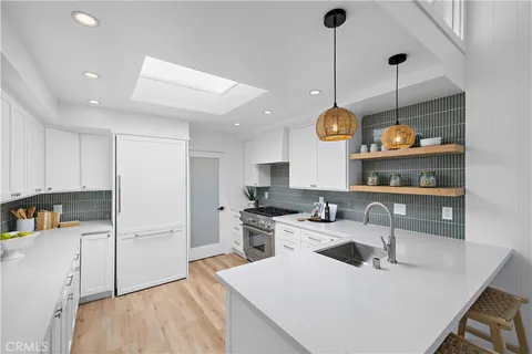 a kitchen with stainless steel appliances granite countertop a sink a stove and a wooden floors