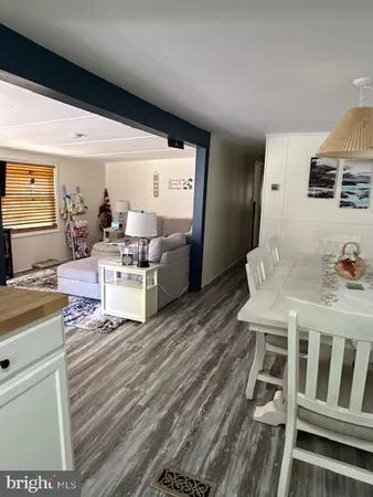 a living room with stainless steel appliances furniture a rug and a view of kitchen