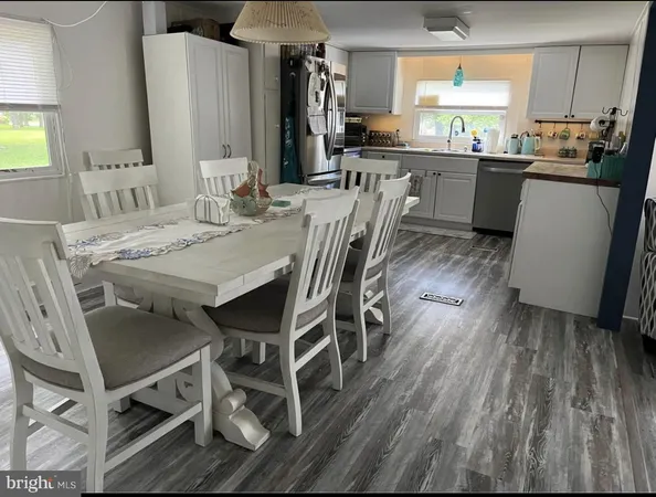 a kitchen with stainless steel appliances kitchen island granite countertop a table chairs sink and cabinets