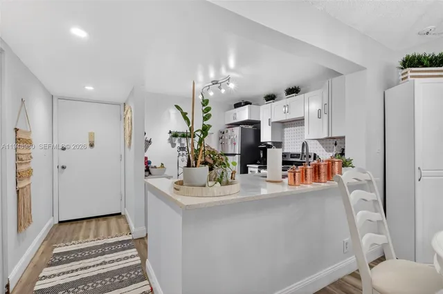 a dining room with stainless steel appliances kitchen island granite countertop a refrigerator and a sink