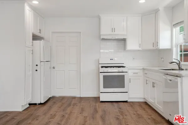 a kitchen with granite countertop white cabinets and stainless steel appliances