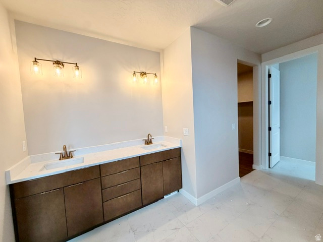 5885 Canyon Rim Road, Unit 624 Lehi, UT 84048 - Photo 6 of 10 Dual vanity with integrated sinks and white countertops, rich wood-tone cabinetry, and brushed gold fixtures