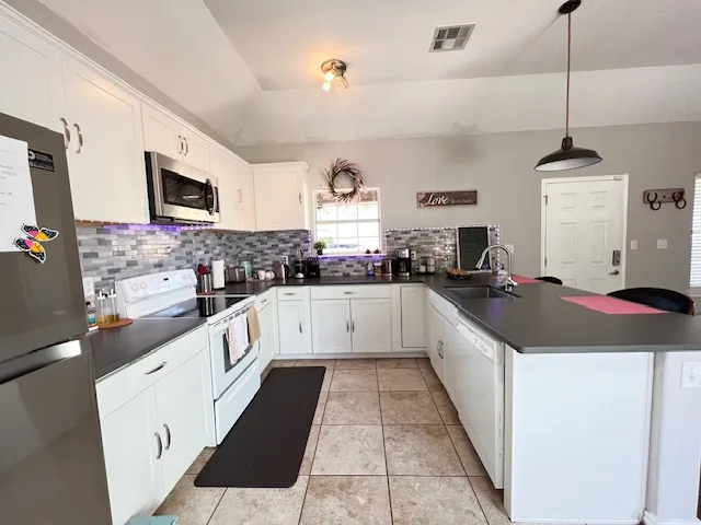 a large white kitchen with stainless steel appliances granite countertop a stove a sink and a refrigerator