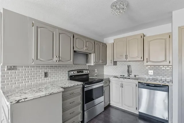 a kitchen with white cabinets sink and appliances