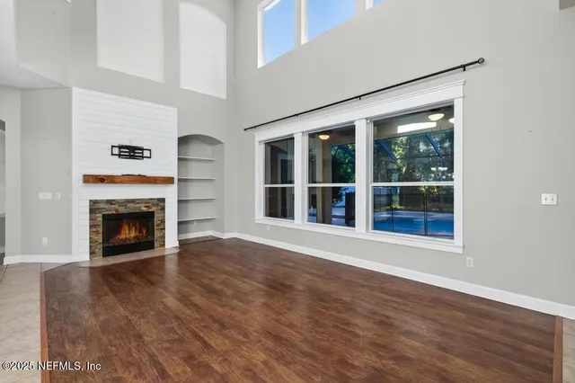 a view of an empty room with wooden floor and a fireplace