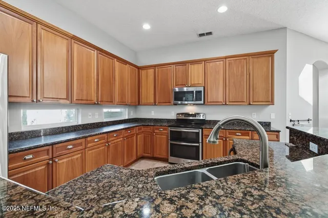 a kitchen with stainless steel appliances granite countertop a stove sink and cabinets