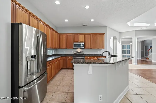 a kitchen with stainless steel appliances granite countertop a refrigerator a sink a stove a microwave and island
