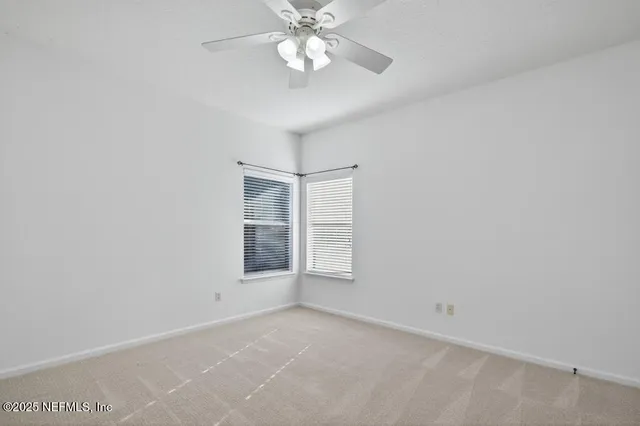 an empty room with windows and fan