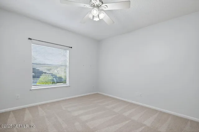 an empty room with a window and a ceiling fan