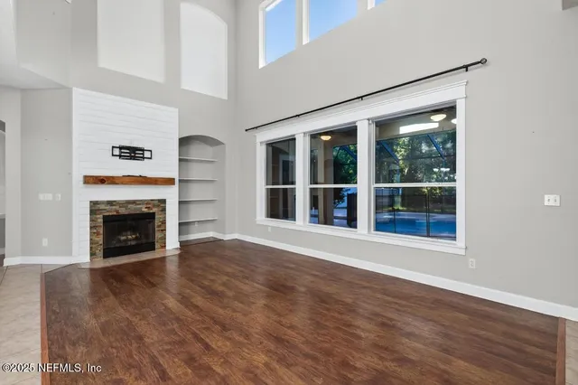 a view of an empty room with wooden floor and a fireplace
