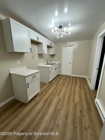 a large white kitchen with a sink a refrigerator and window