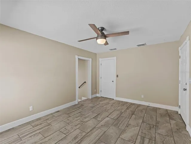 a view of a big room with wooden floor and a ceiling fan