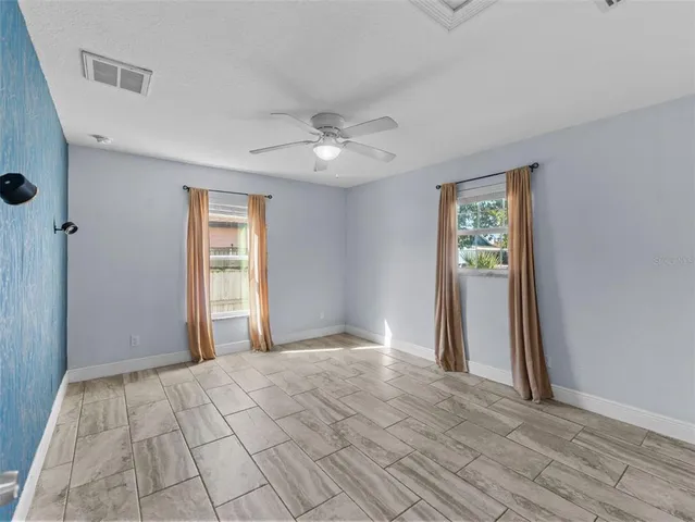 a view of empty room with window and ceiling fan