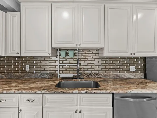 a kitchen with granite countertop white cabinets and white appliances