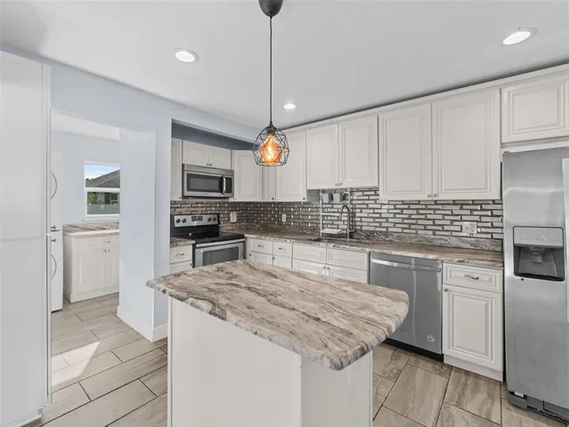 a kitchen with granite countertop a sink a counter space stainless steel appliances and cabinets