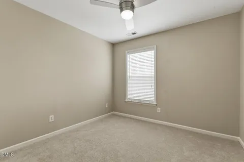 an empty room with a chandelier fan and windows