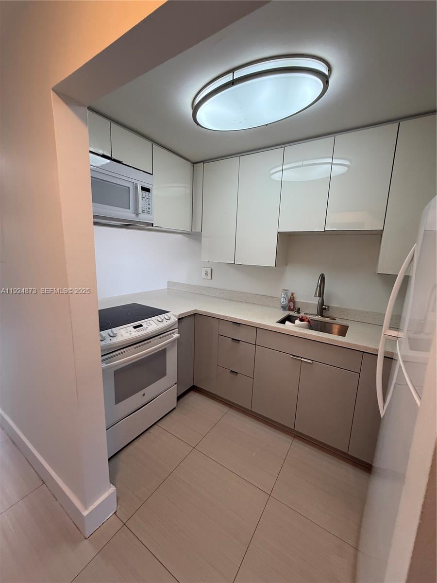 13215 Southwest 57th Terrace, Unit 206 Miami, FL 33183 - Photo 24 of 27 a kitchen with a stove cabinets and a sink