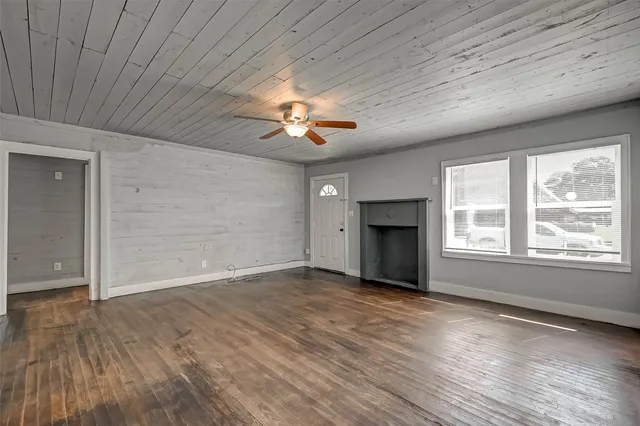 a view of an empty room with a window and wooden floor