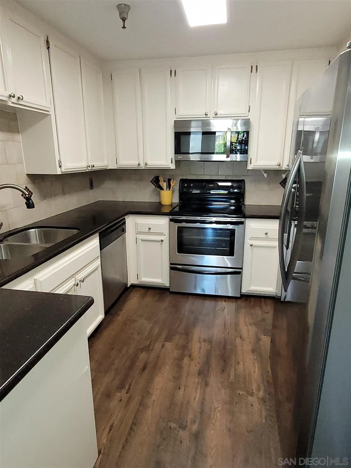 5605 Friars Road, Unit 285 San Diego, CA 92110 - Photo 5 of 11 a kitchen with stainless steel appliances and white cabinets