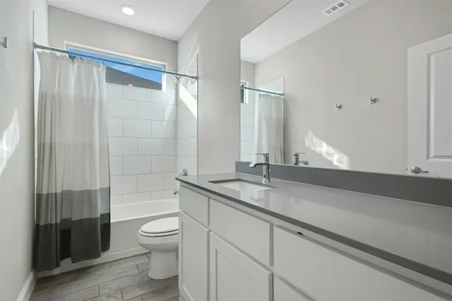 a bathroom with a granite countertop sink a toilet and shower